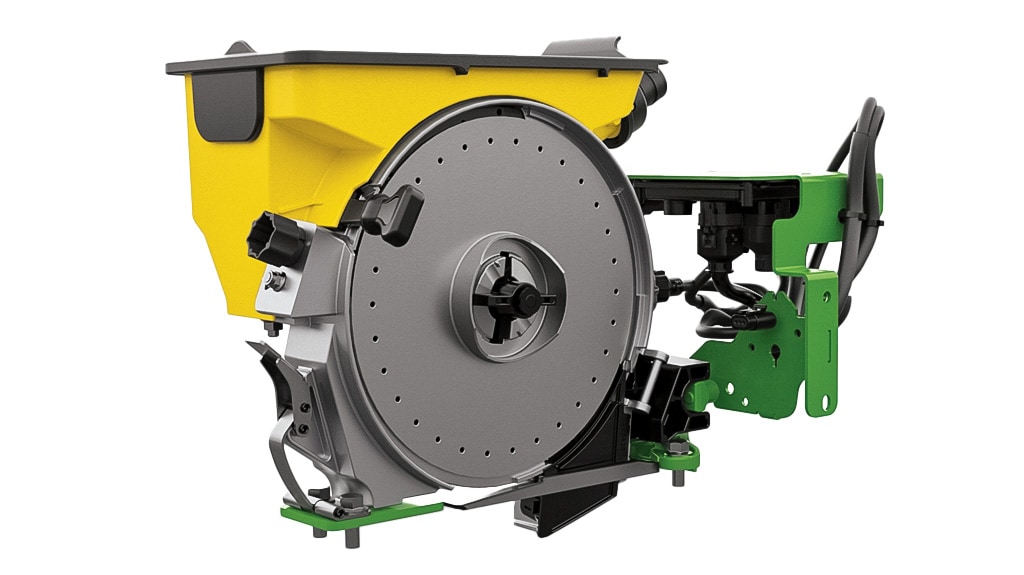 Studio image of a John Deere seed meter assembly, showing the yellow seed hopper, gray seed disk, and green mounting bracket with electronic components.