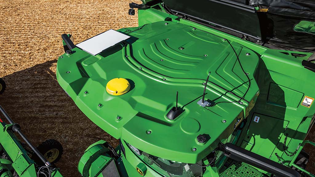 Overhead view of a combine roof showing a mounted GPS receiver and antennas in a harvested field.