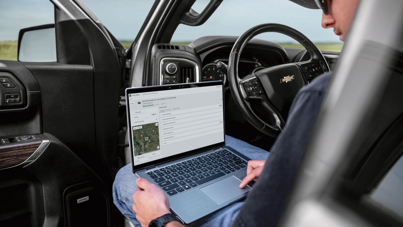 Une personne assise dans une cabine de ramasseur examine une carte de champ sur un ordinateur portable.