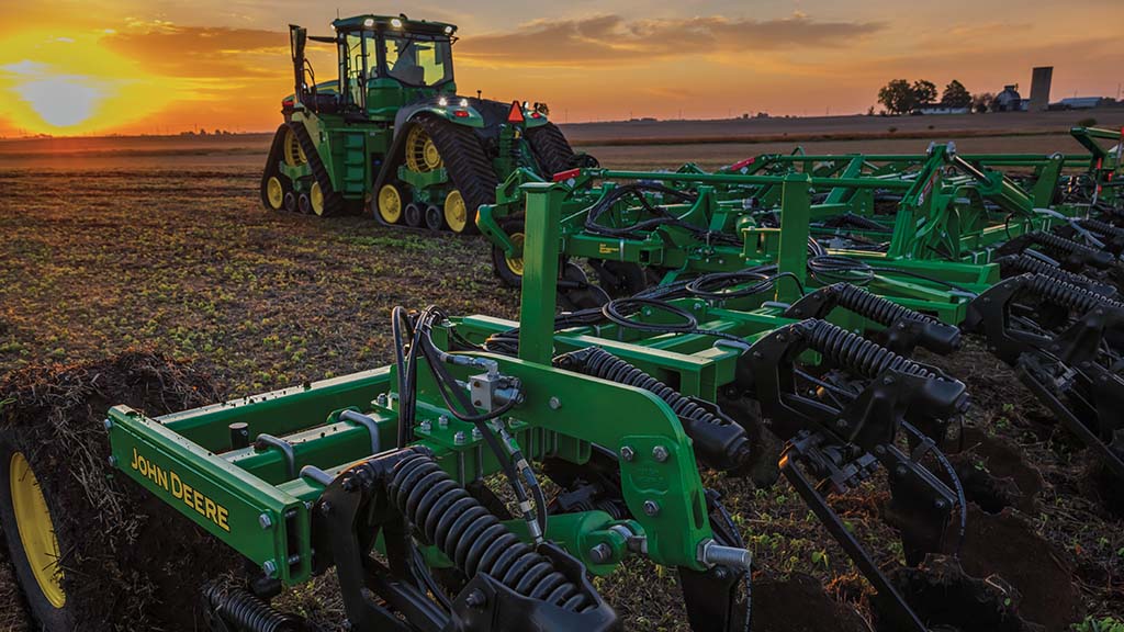 John Deere 2430C nutrient applicator operating in a field under a clear sky.