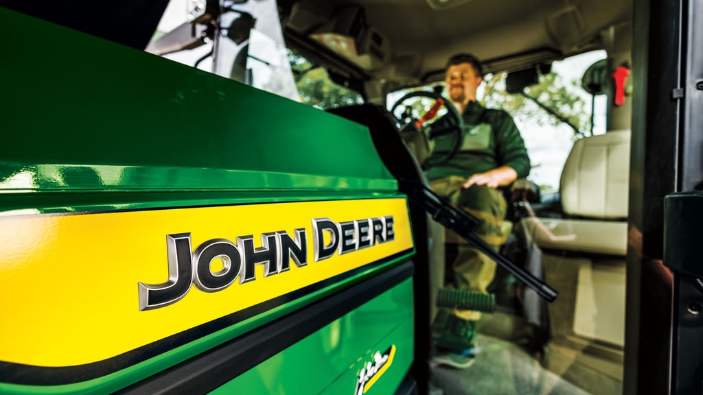 View from outside showing a farmer sitting in the 6R cab.