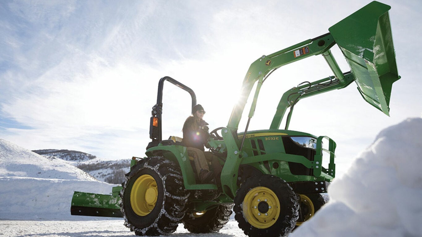 person dumping snow from the loader of a 3032e