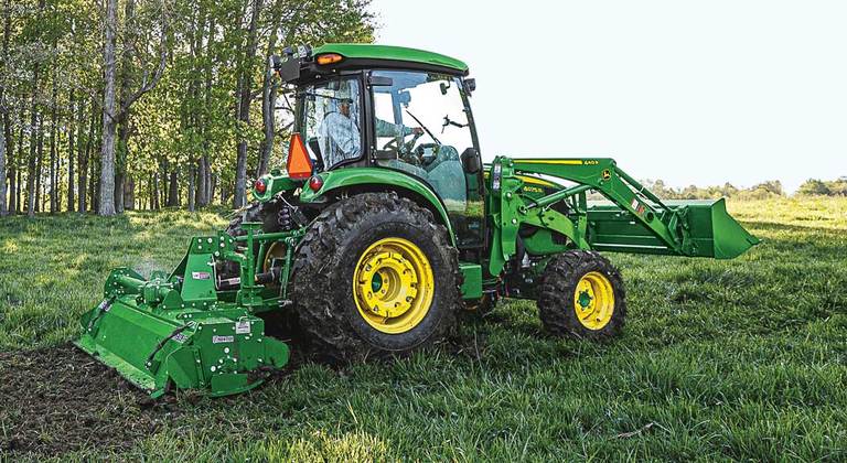 Person tilling field with a Frontier rotary tiller on a 4075R Compact Utility Tractor