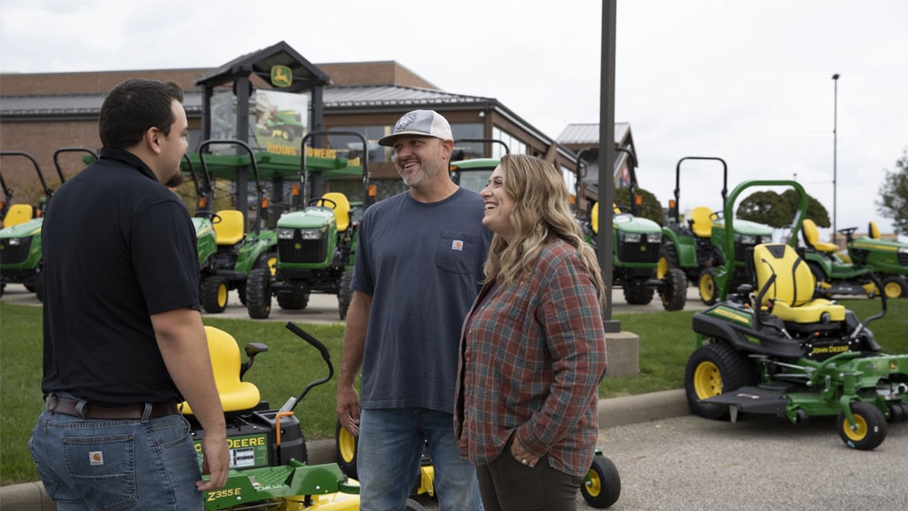 people smiling with John Deere dealer at dealership lot