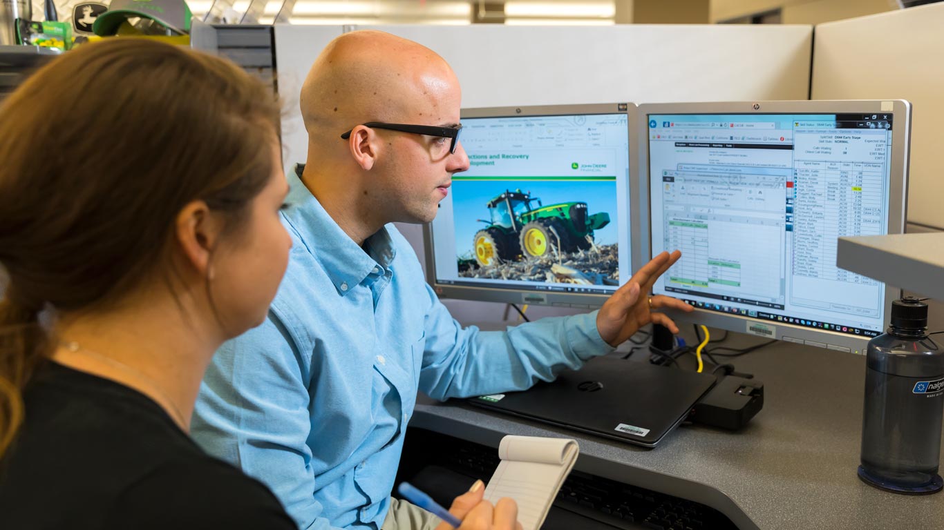 a man and a woman working in front of computer monitors