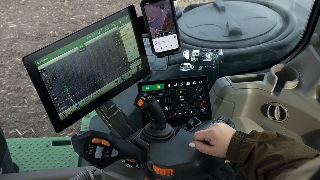 Vue de l’intérieur de la cabine d’un tracteur John Deere de la série&nbsp;8, équipée d’une console pratique, d’un chargeur de téléphone sans fil et de commandes de transmission CommandX™