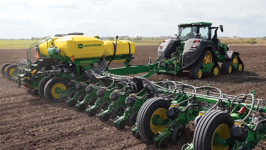 Tracteur&nbsp;8R tirant un semoir dans un champ.