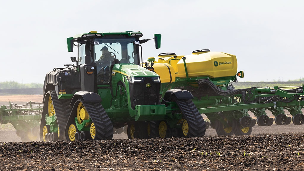 Un John Deere 8RX 410 effectue un virage tout en tirant un semoir tracté 1775NT dans un champ