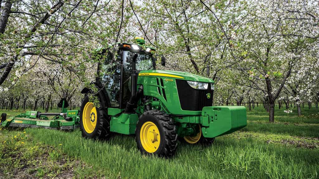 Tracteur John Deere tirant un instrument dans l'herbe