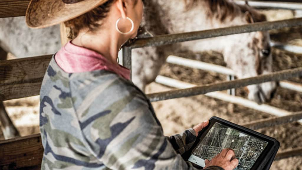 femme dans une écurie utilisant JDLink sur une tablette