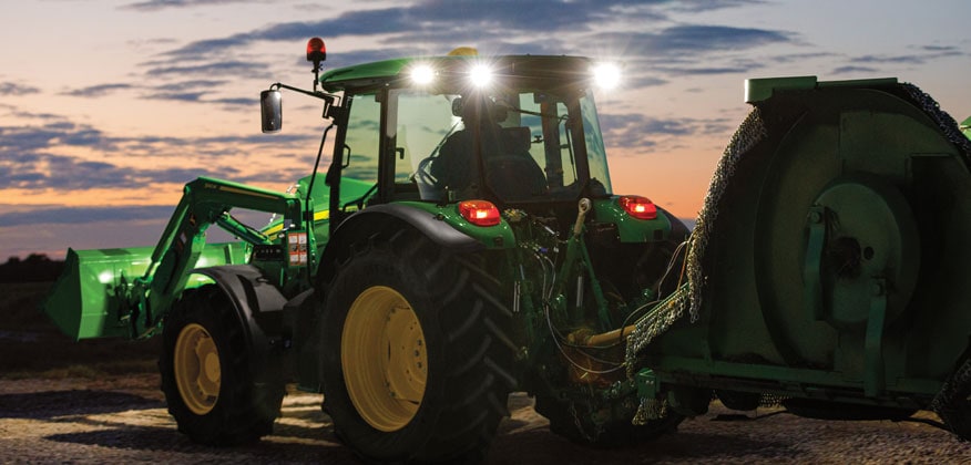 tracteur 5M avec feux et phares allumés au crépuscule