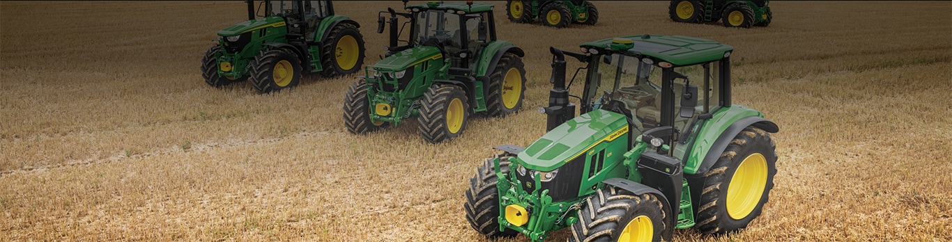 Various 6M Tractors parked in a field