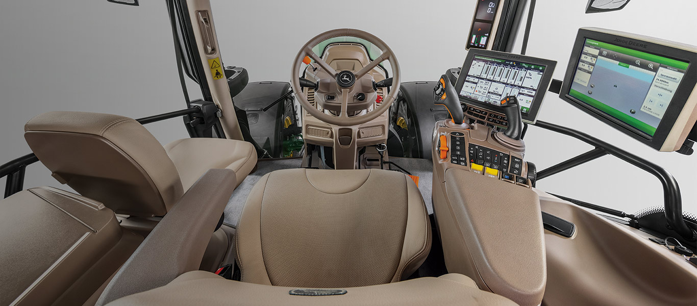 tractor cab with multiple computer monitors, joysticks, and controls