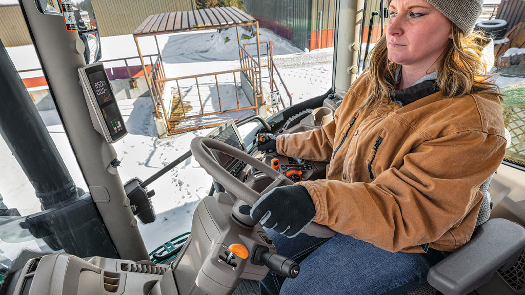 person in tractor cab holding steering wheel