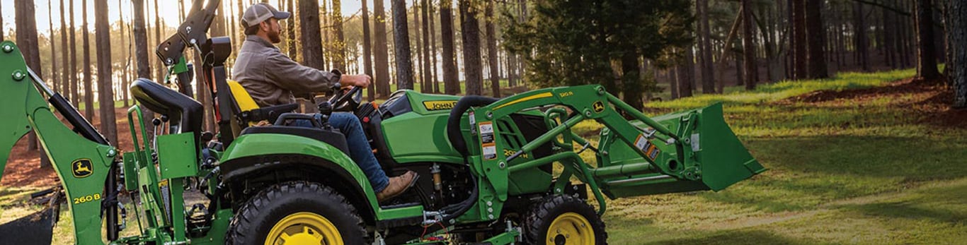 person riding a compact tractor in a forest