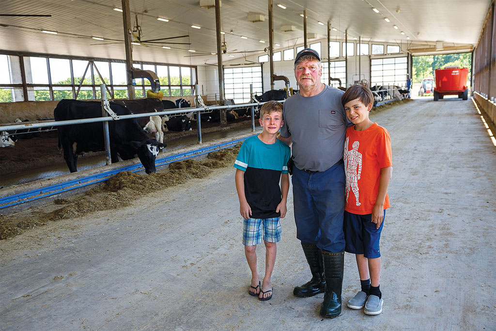 man with boys stating in front of cows