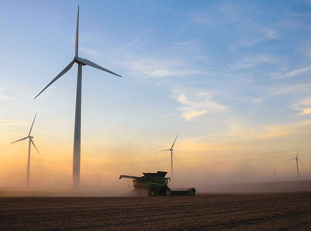 combine in field with wind turbines