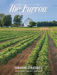 Crop rows with farm in background