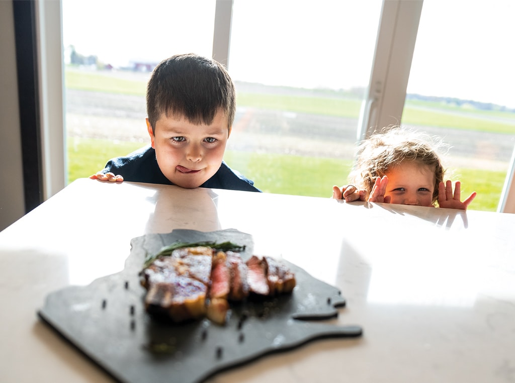 Kids looking over a table at food.