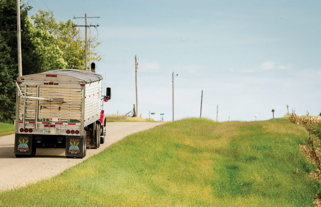 truck driving down road past crops