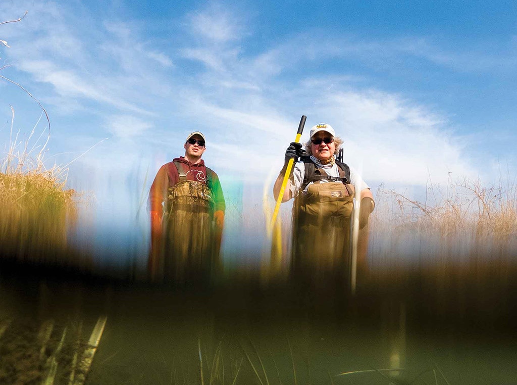 trout farmers standing in shallow stream waters