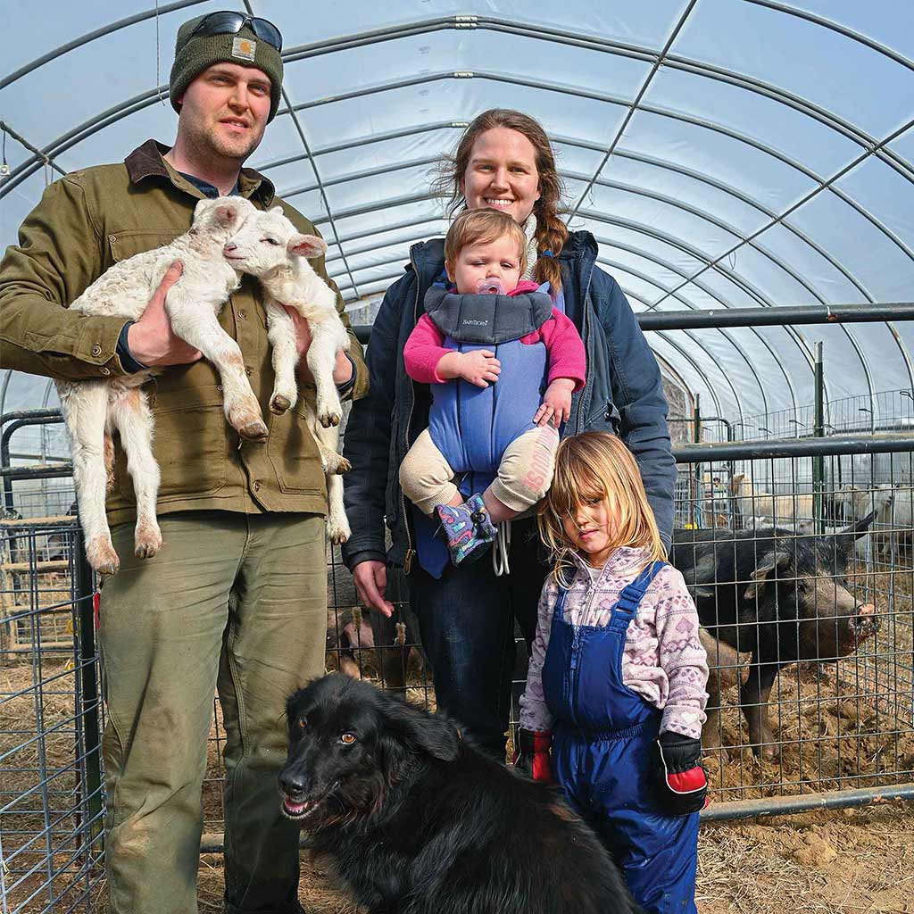 farming family with baby sheep and dog