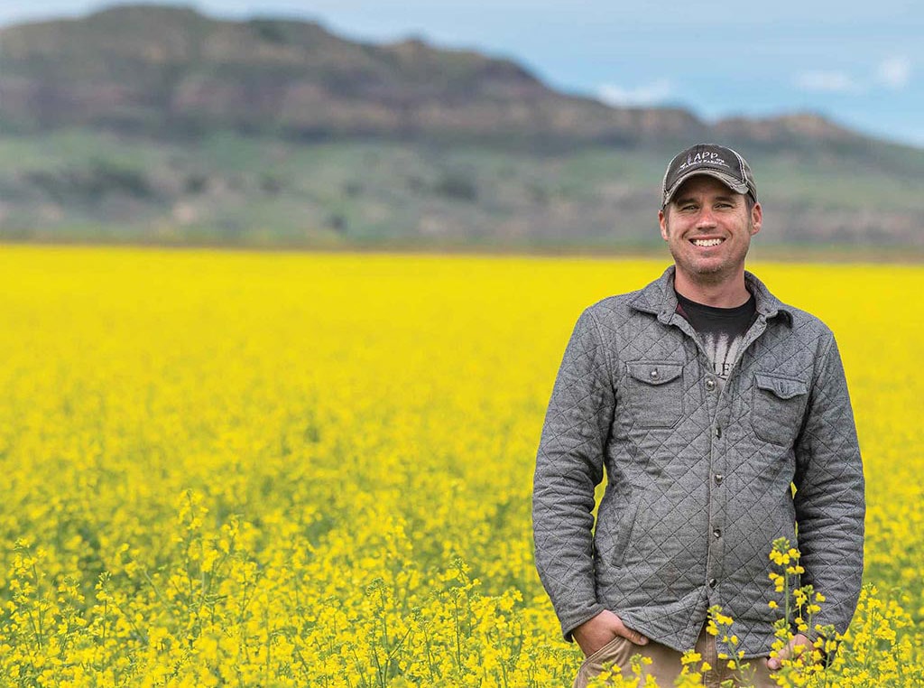 man standing in field of canola crops