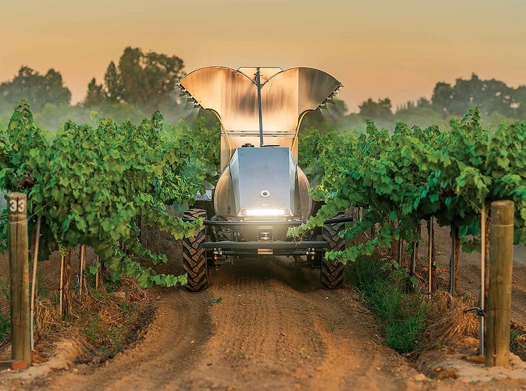 orchard sprayer between rows of trees in an orchard