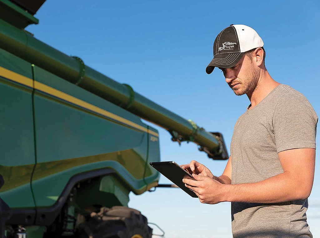 Homme se servant d'une tablette aux côtés d'une machine de John Deere