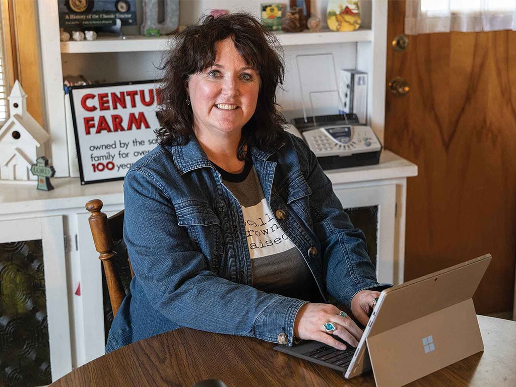 smiling woman at desk typing on tablet laptop