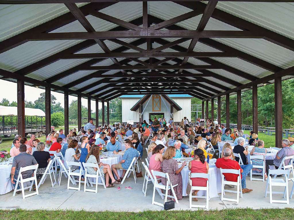 people gathered dining at tables in an outdoor pavillion