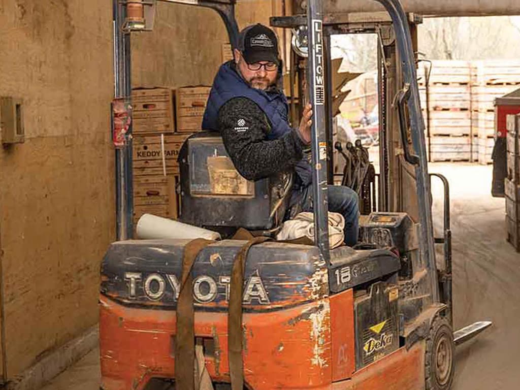 Homme reculant un chariot élévateur à fourche dans un entrepôt