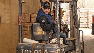 Homme reculant un chariot élévateur à fourche dans un entrepôt
