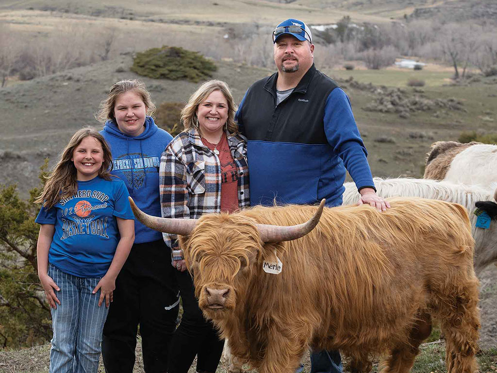 Famille qui élève du bétail à côté d’une vache Highland miniature