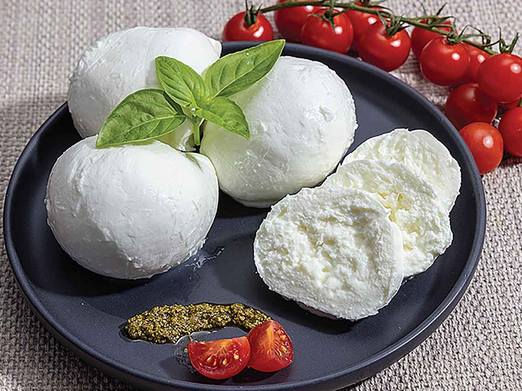 balls and slices of fresh mozzarella cheese on a plate surrounded by red cherry tomatoes