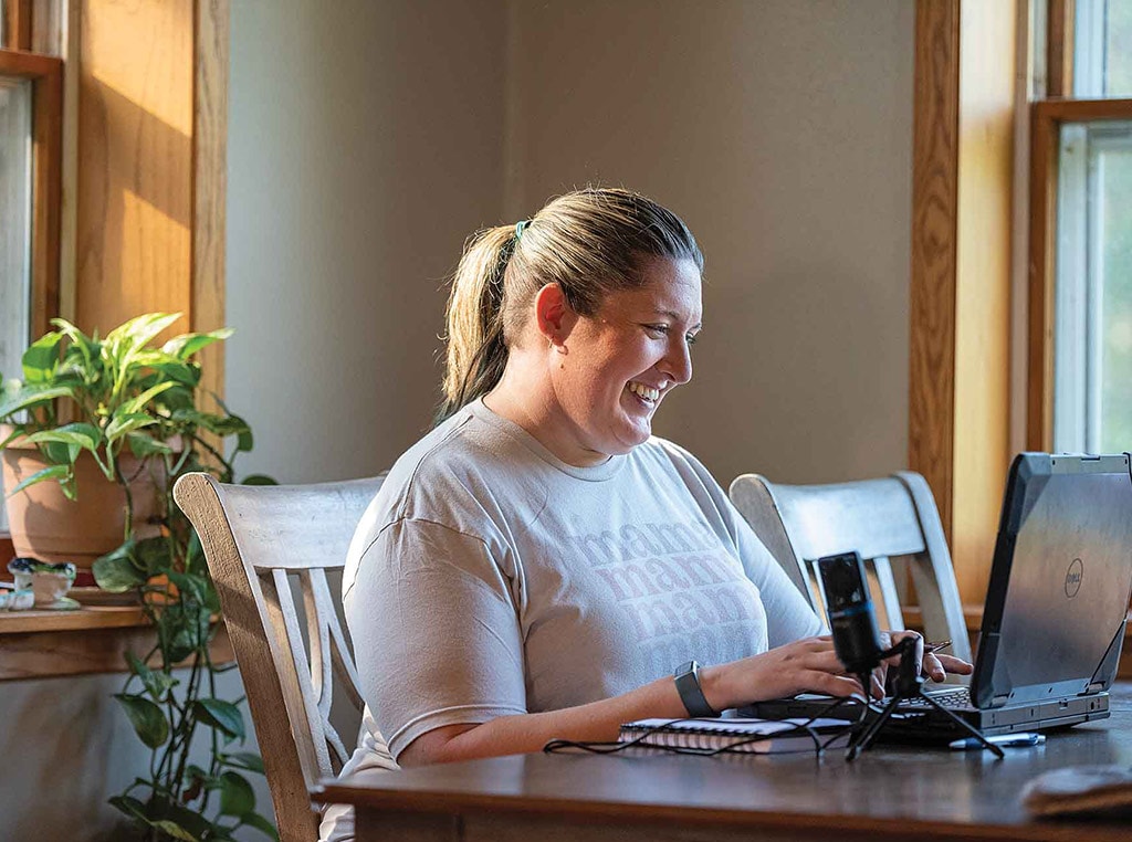 woman smiling while typing on laptop computer