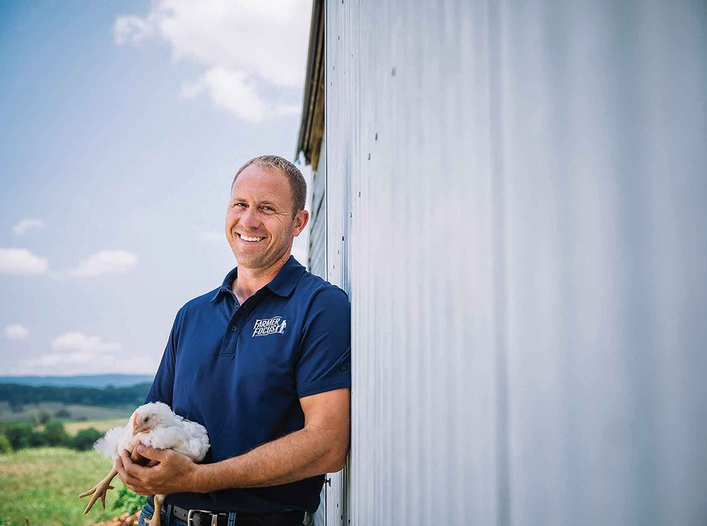 man in blue shirt holding chicken