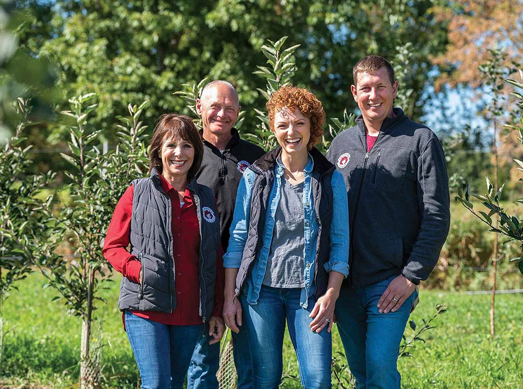 famer family smiling in front of young trees