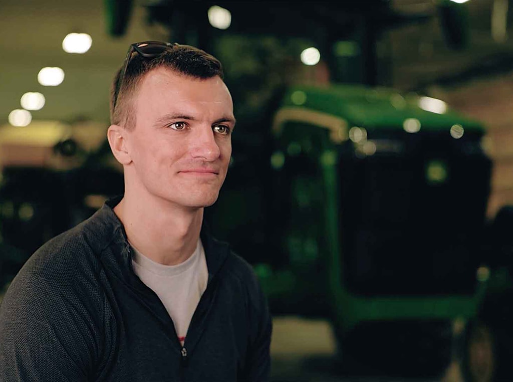 Homme debout devant un tracteur de John Deere