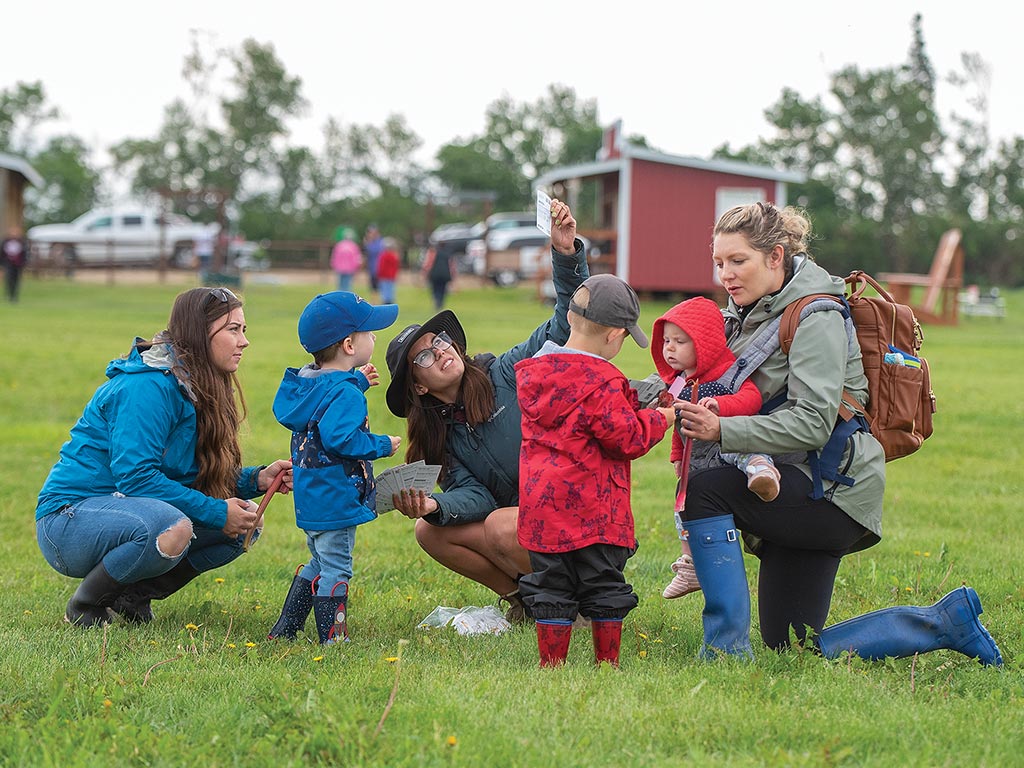 Teachers kneeling and talking to kids in a field