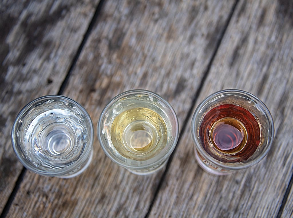 Trois verres à liqueur, vus de haut, contenant des liqueurs colorées
