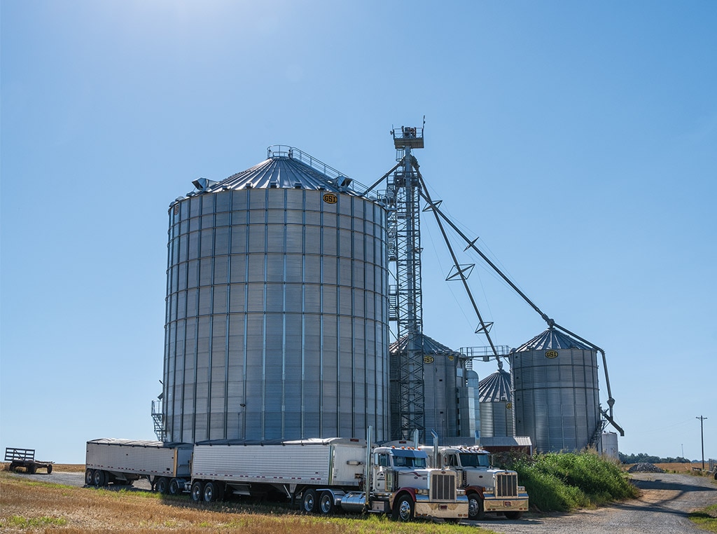 multiple silos with semi trucks in front