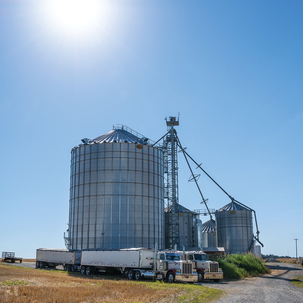 multiple silos with semi trucks in front