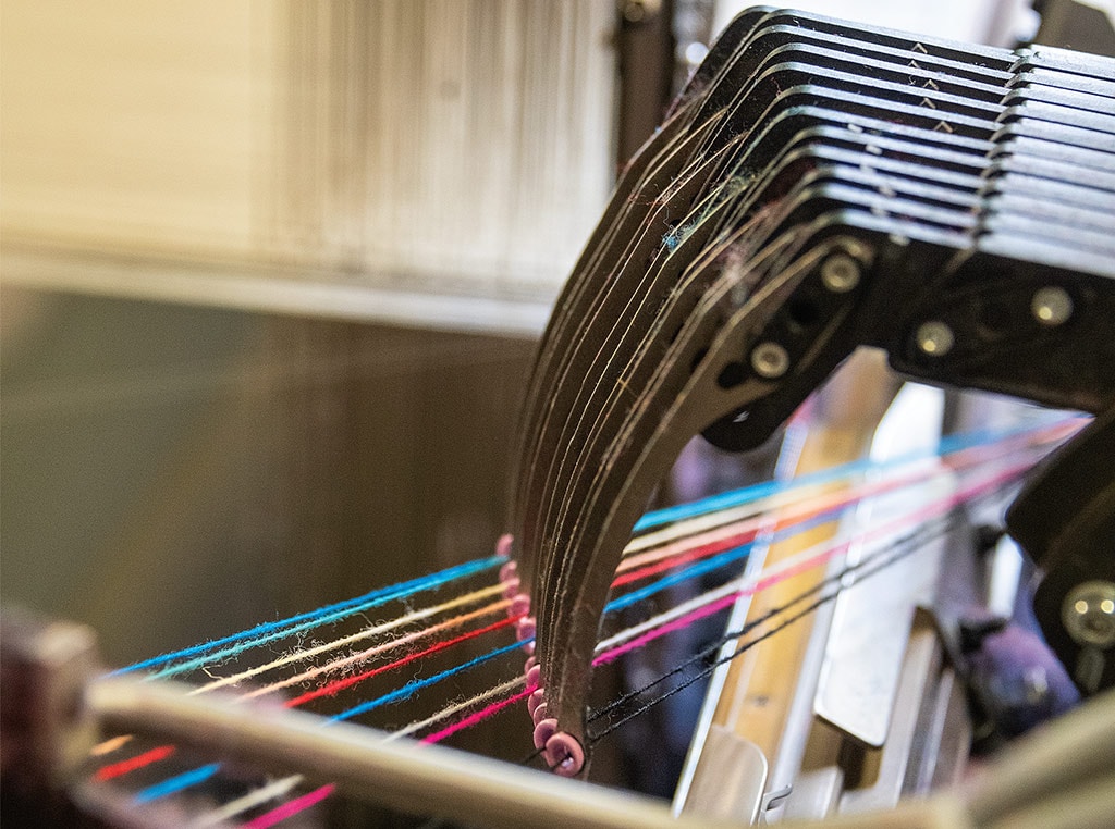 loom with a rainbow of yarn strands passing through small hoops