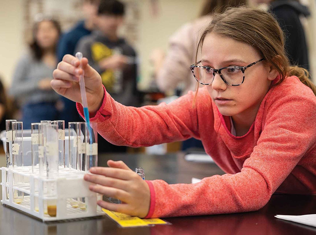 female student with glasses squeezing pipette into test tube