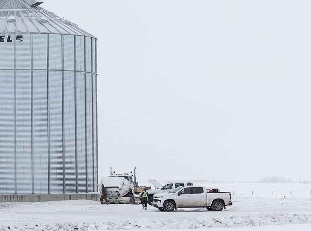 Camionnettes stationnées dans la neige près d’un silo de métal