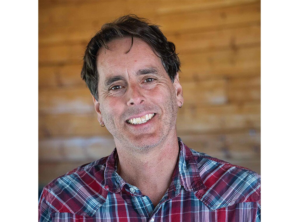 dark haired man in plaid flannel shirt smiling