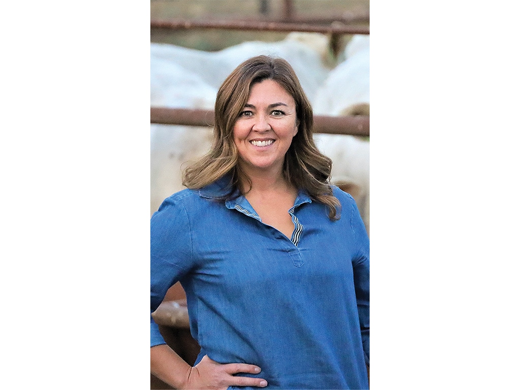 brown-haired person smiling with blue denim shirt on