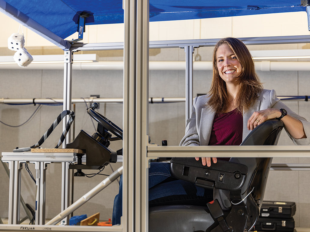 smiling person in a business suit sitting in a driving simulator