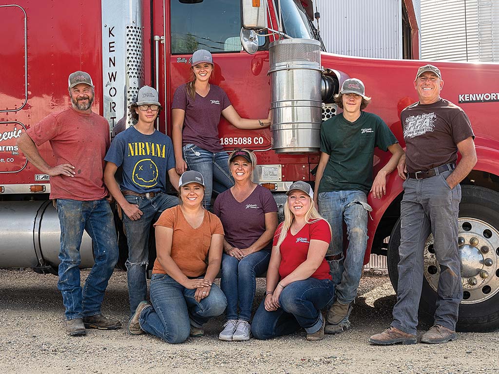 Group of people standing and squatting next to semi-truck